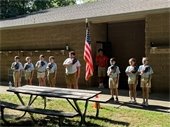 Photo of campers with their caps off next to the American flag