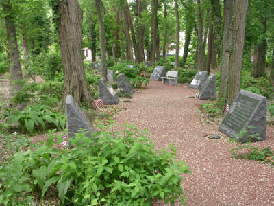 Memorial markers alongside a walking trail in a wooded area